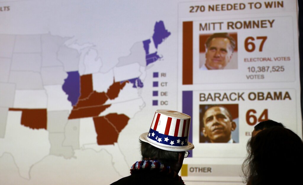 Guests look at early projections for votes for the President Barack Obama and Republican presidential candidate, former Massachusetts Gov. Mitt Romney during the Presidential Election party at the U.S. Embassy in London, Wednesday, Nov. 7, 2012. (AP Photo/Alastair Grant)